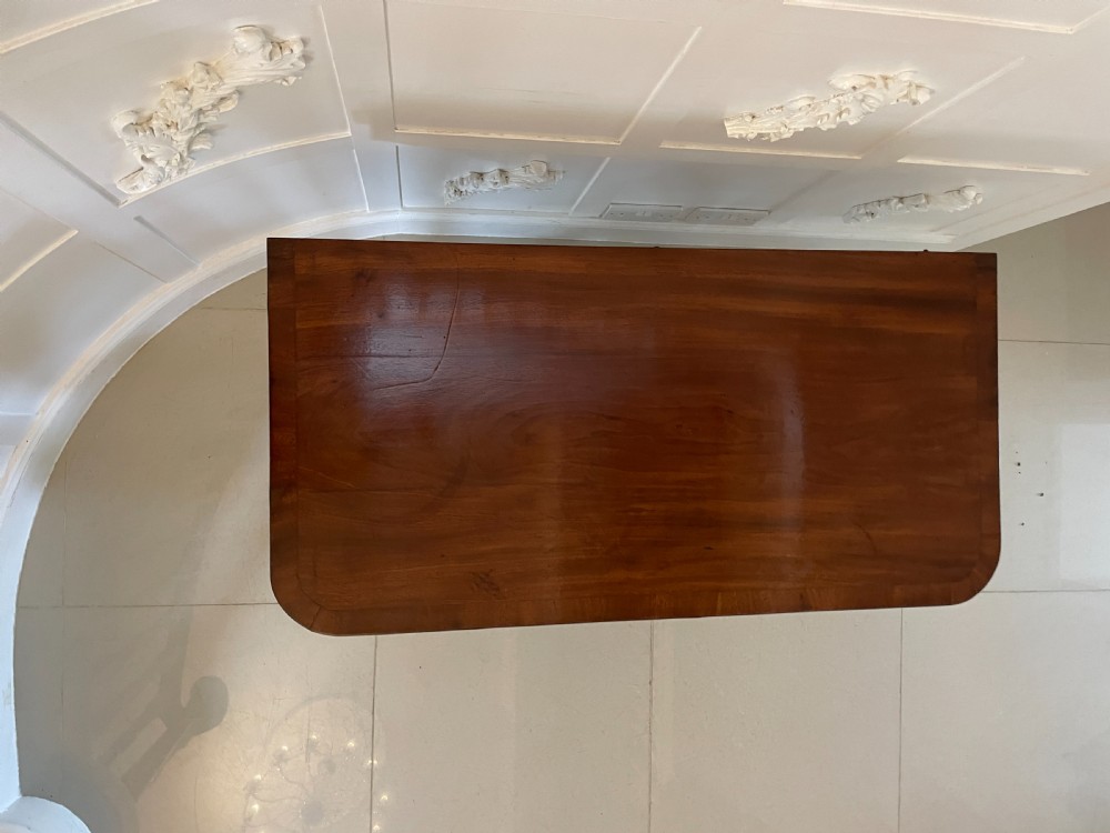 A Regency mahogany fold-over card table featuring a curved support pedestal, carved rosette scrolls, and four splayed legs fitted with brass castors. View VI