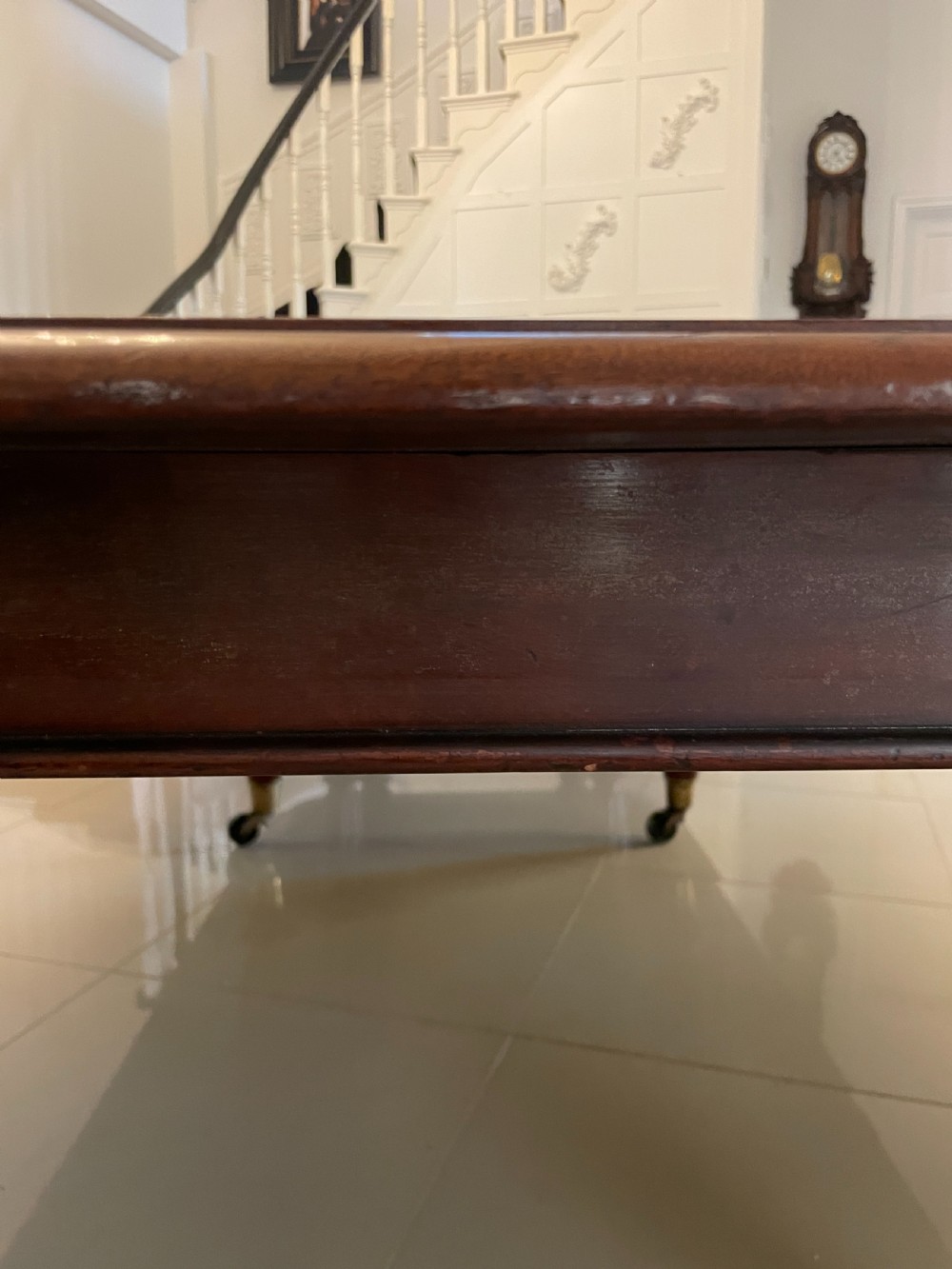 A long, highly polished Victorian mahogany dining table with rounded corners, inserted extension leaves, fluted turned legs, and brass castors. View XI