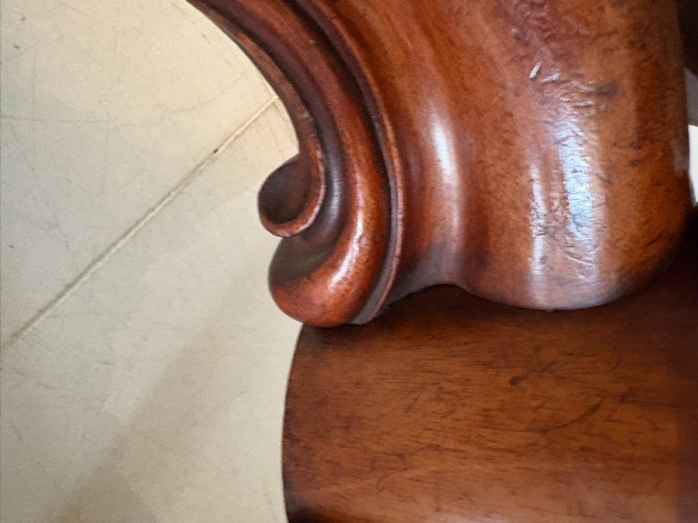 An antique Victorian oval tilt-top dining table in figured mahogany with a satinwood crossbanded border tilted vertically on a quadform pedestal base. View X
