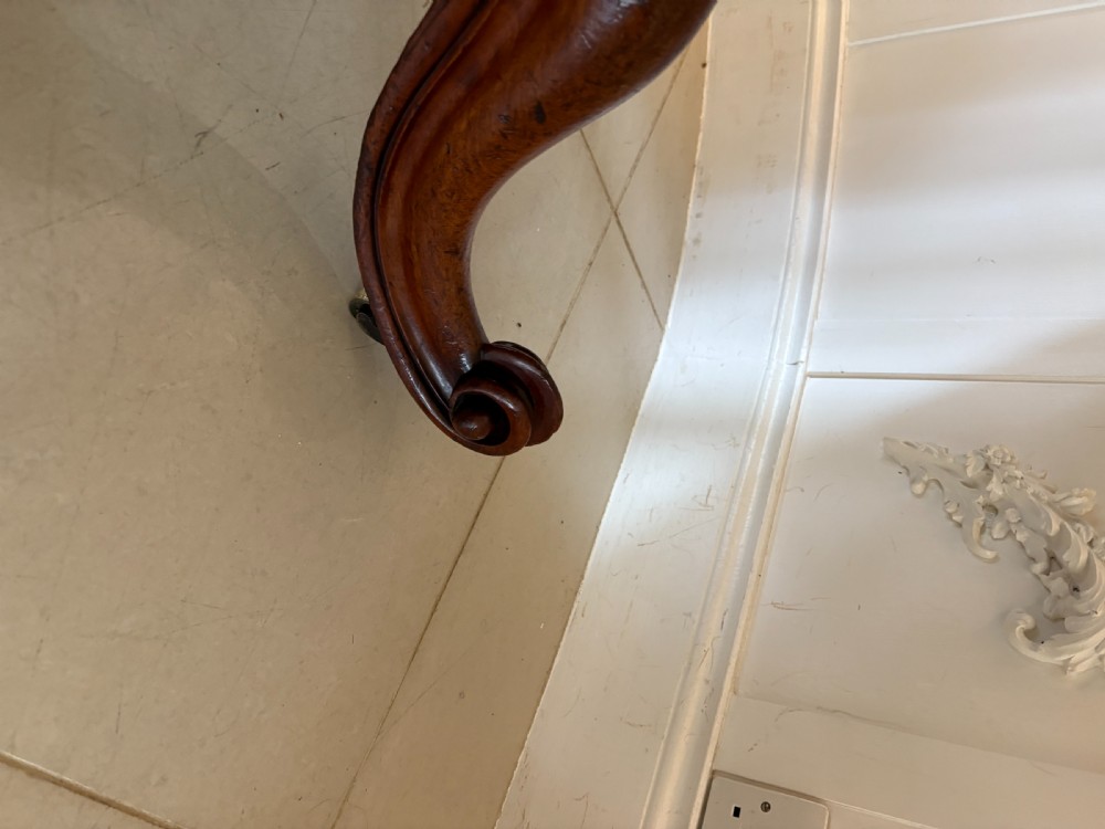 An antique Victorian oval tilt-top dining table in figured mahogany with a satinwood crossbanded border tilted vertically on a quadform pedestal base. View XI