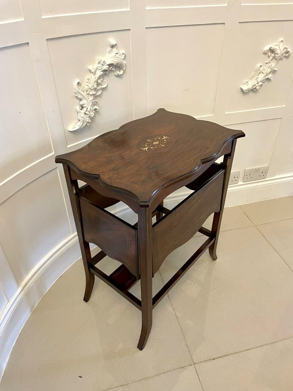 An Edwardian dark rosewood side table featuring a serpentine-shaped top with central floral marquetry inlay and splayed legs.