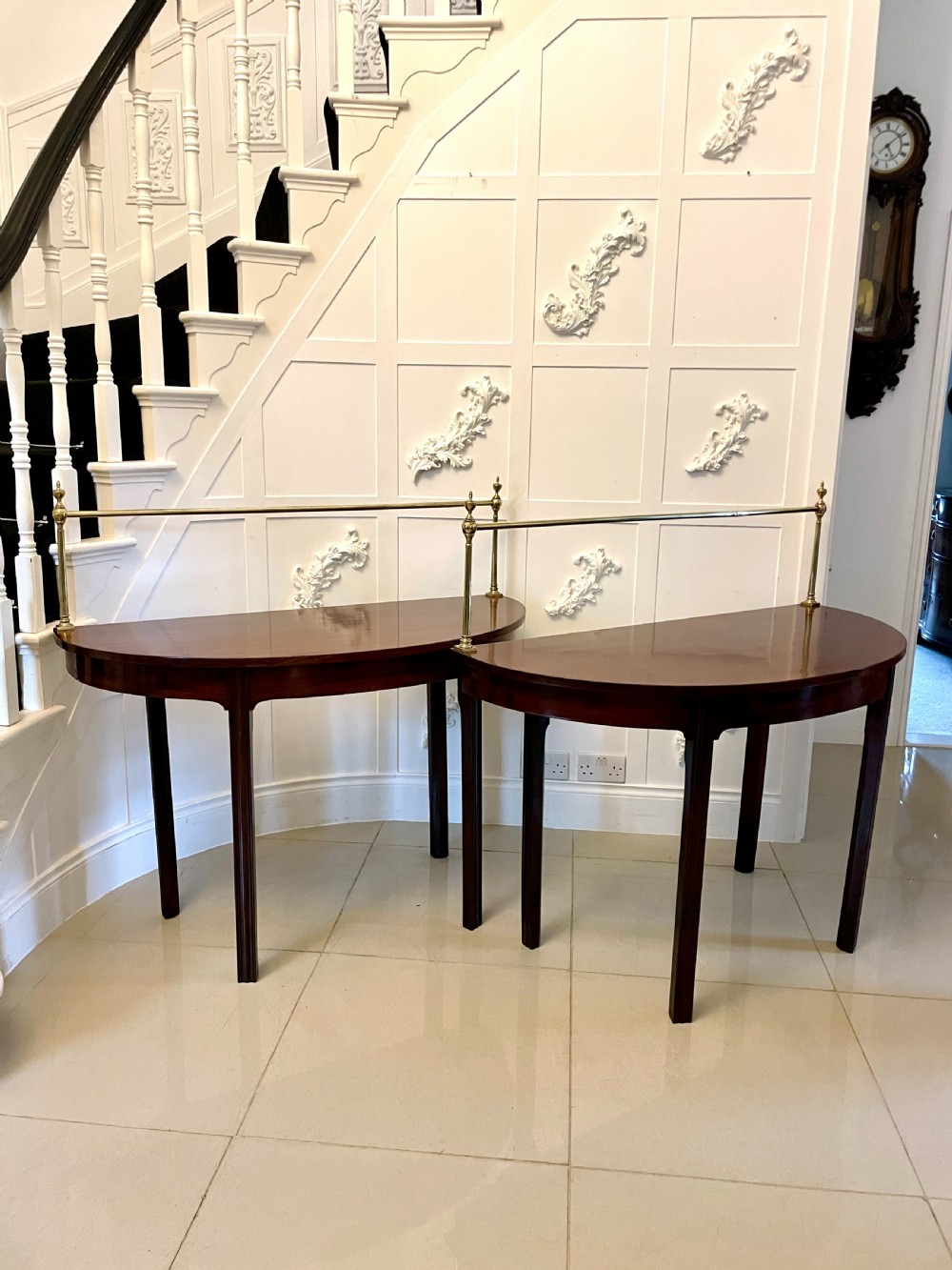 A pair of antique George III mahogany demi-lune console tables featuring raised brass gallery rails and square tapered legs.