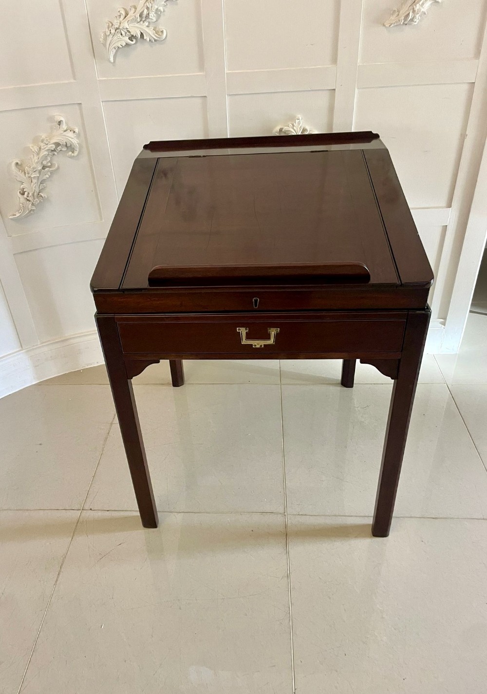 A George III mahogany slant-top writing desk with a front book rest, single drawer with a brass handle, and four straight legs.