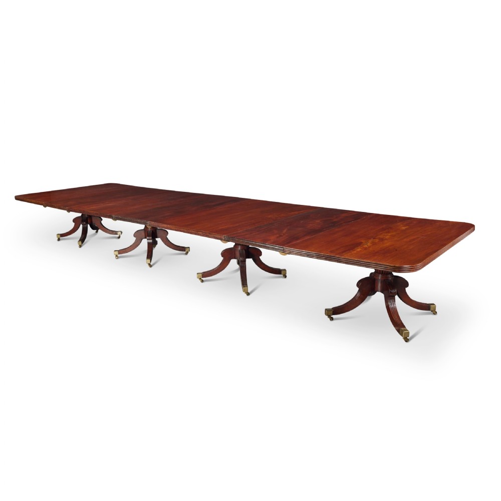 An exceptionally long antique mahogany Regency dining table supported by four reeded pedestal bases with brass castors. View VII