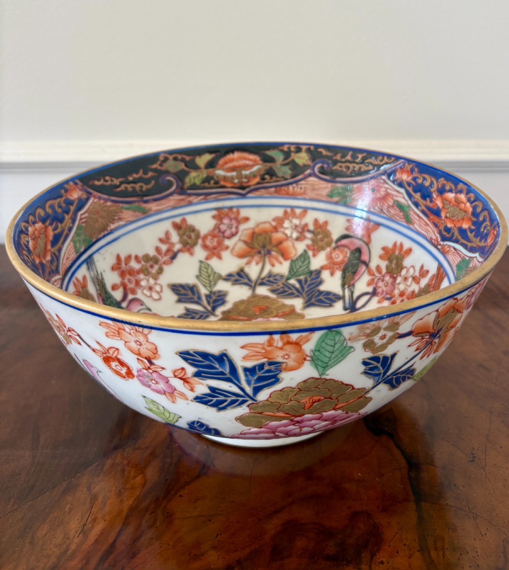 A deep Japanese Imari porcelain bowl hand-painted with cobalt blue, pink, and iron-red floral motifs, finished with a gilded rim.