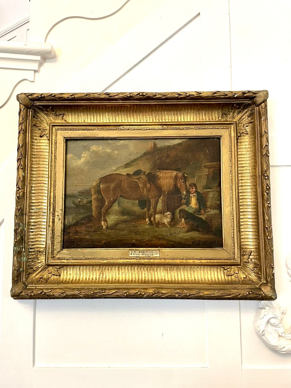 A 19th-century Victorian oil painting depicting a saddled brown horse, two dogs, and a figure in a coastal landscape, housed within an ornate gilded wooden frame.