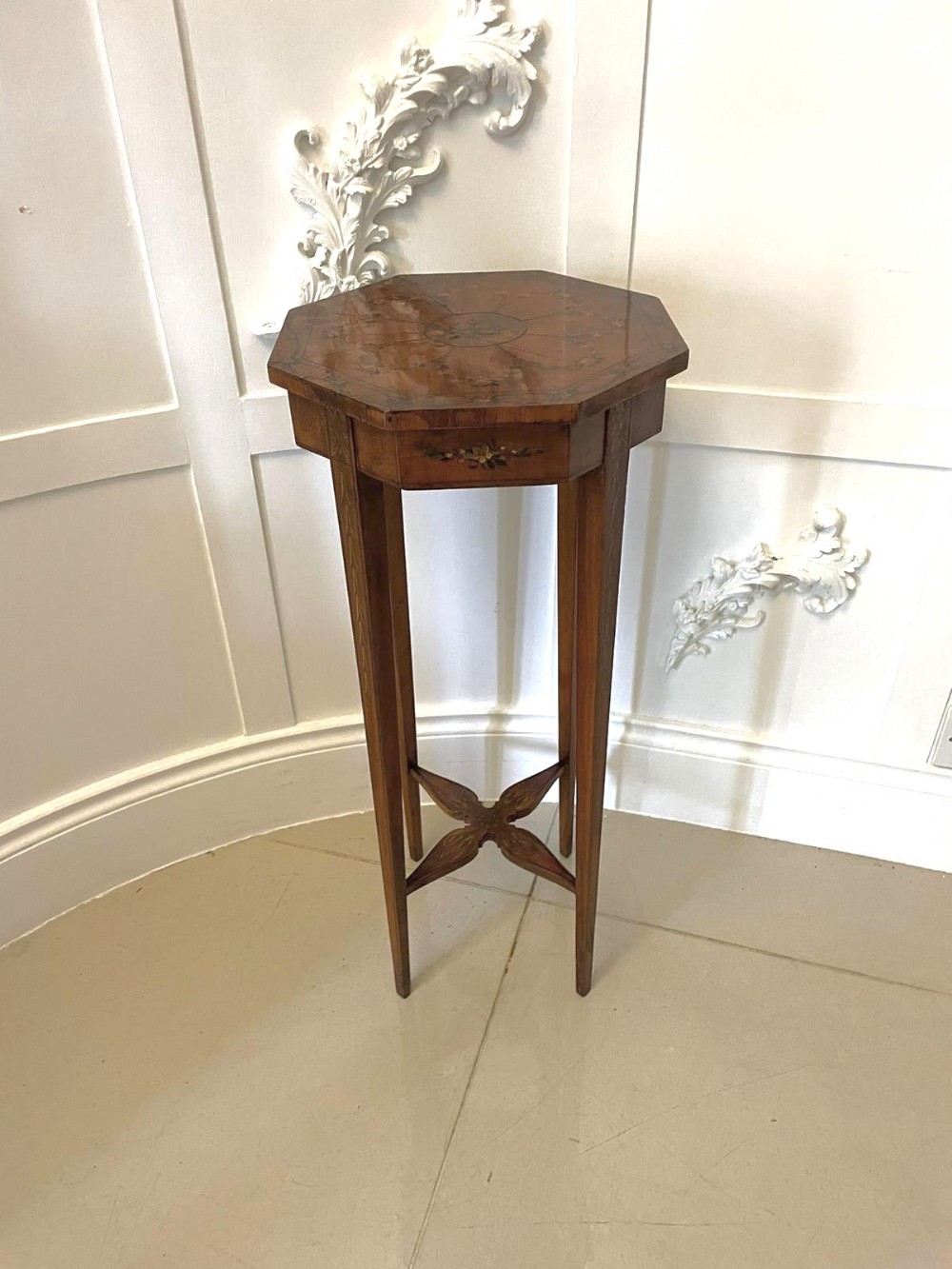 An octagonal Victorian satinwood lamp table featuring hand-painted floral decoration, slender tapered legs, and an X-shaped stretcher.