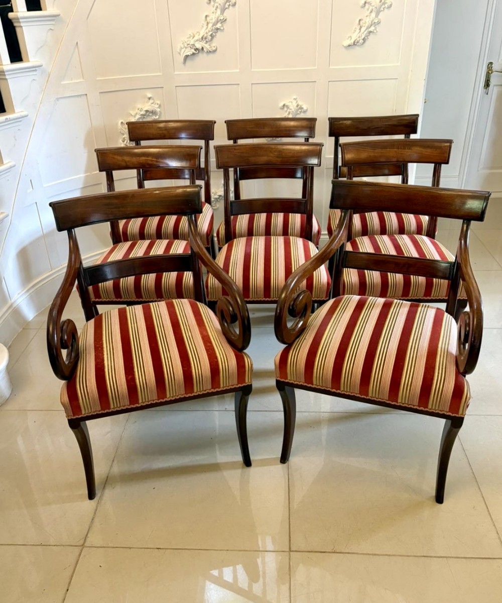 A set of eight mahogany Regency dining chairs with red and cream striped upholstered seats and two carver armchairs featuring carved scroll arms.