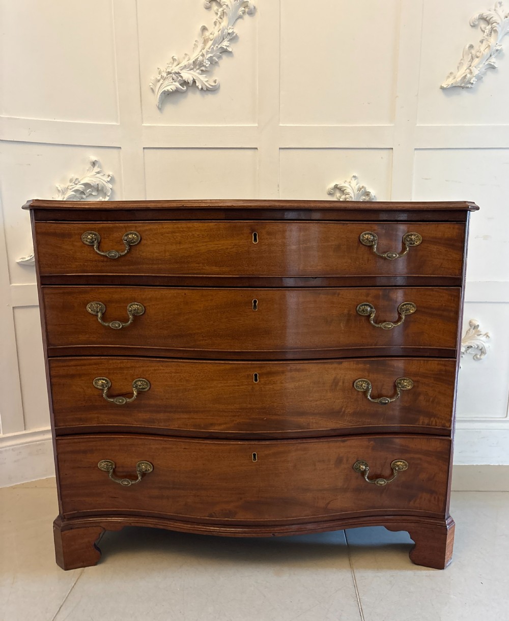 An 18th-century Georgian mahogany chest of drawers featuring a serpentine curved front, four graduated drawers with brass handles, and bracket feet.
