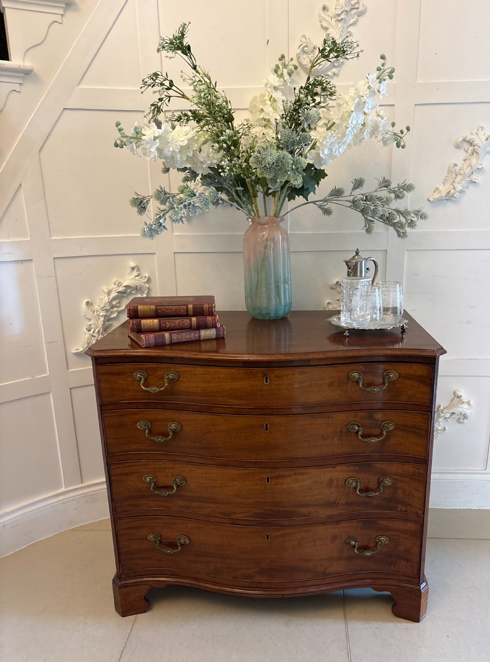 An 18th-century Georgian mahogany chest of drawers featuring a serpentine curved front, four graduated drawers with brass handles, and bracket feet. View II