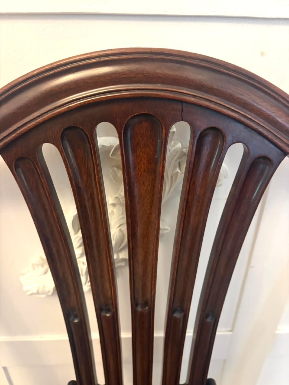 A set of Victorian mahogany Hepplewhite style dining chairs featuring shield-shaped backs with carved splats and tan leather upholstered seats. View VI