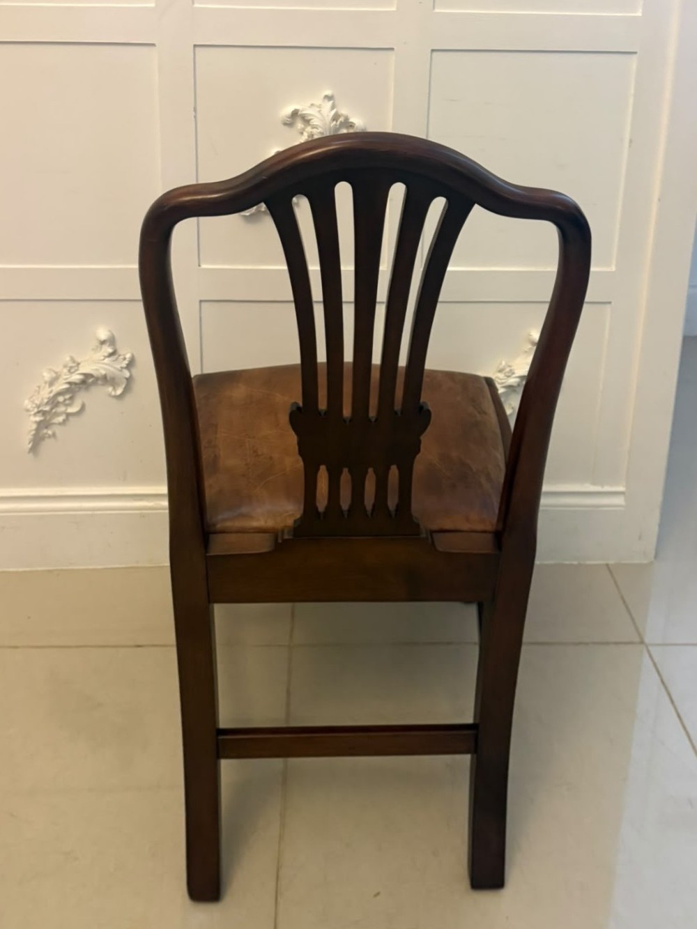 A set of Victorian mahogany Hepplewhite style dining chairs featuring shield-shaped backs with carved splats and tan leather upholstered seats. View VII