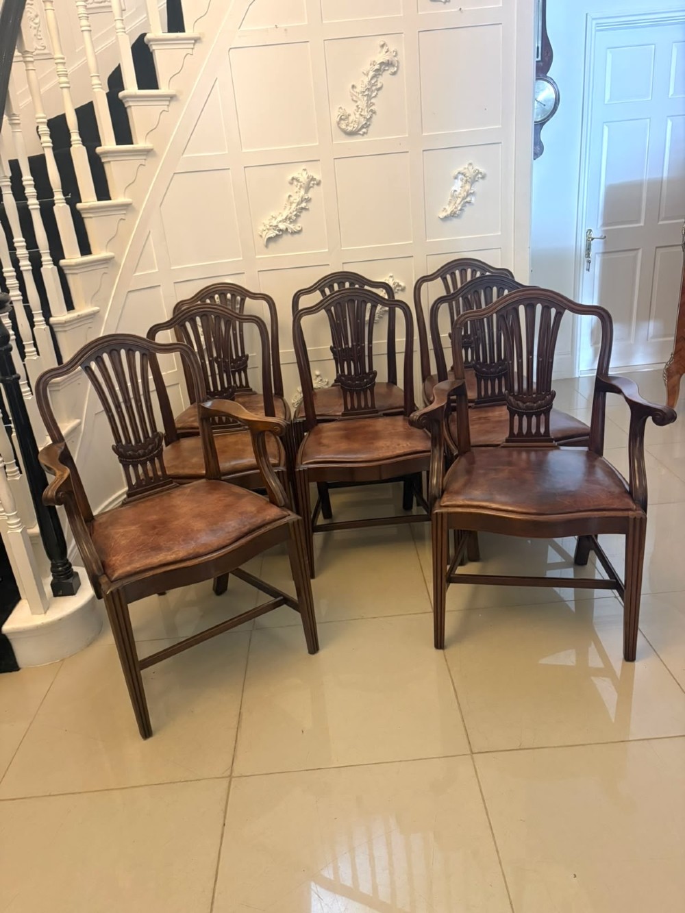 A set of Victorian mahogany Hepplewhite style dining chairs featuring shield-shaped backs with carved splats and tan leather upholstered seats. View XI
