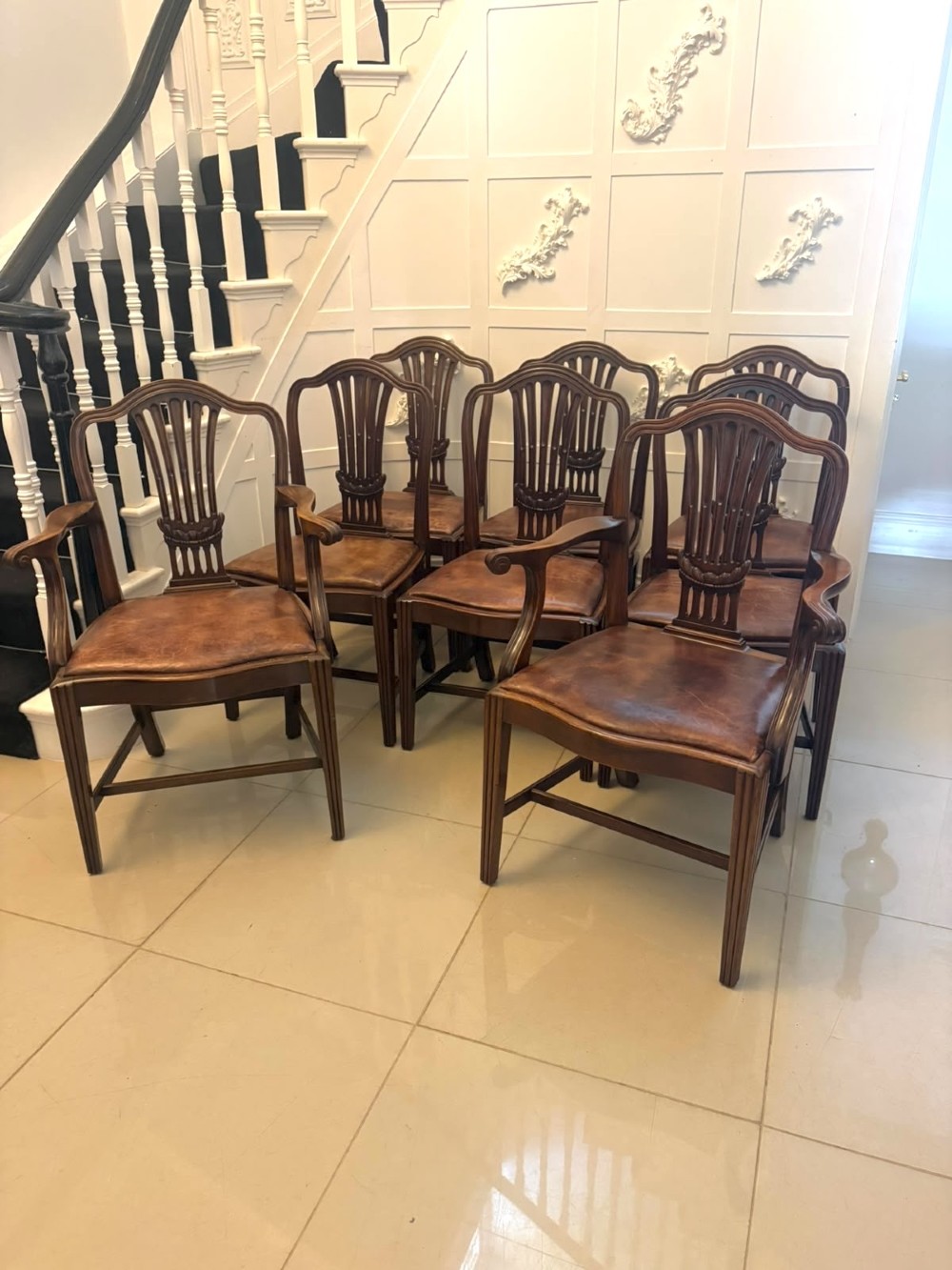 A set of Victorian mahogany Hepplewhite style dining chairs featuring shield-shaped backs with carved splats and tan leather upholstered seats. View XII