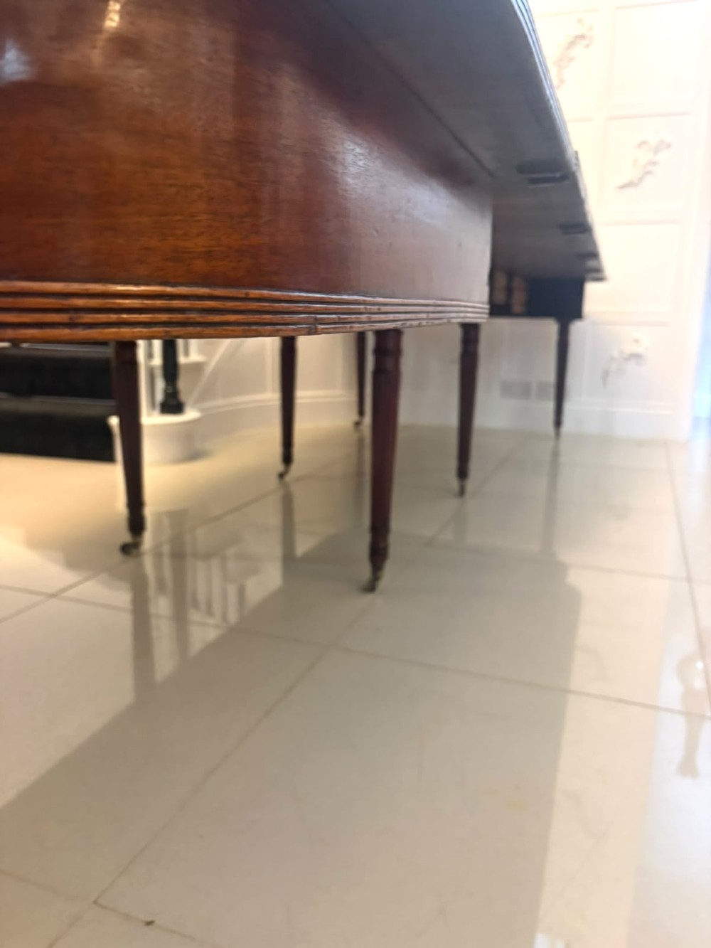 A large, polished Regency mahogany extending dining table with rounded corners and reeded legs fitted with brass castors. View VI