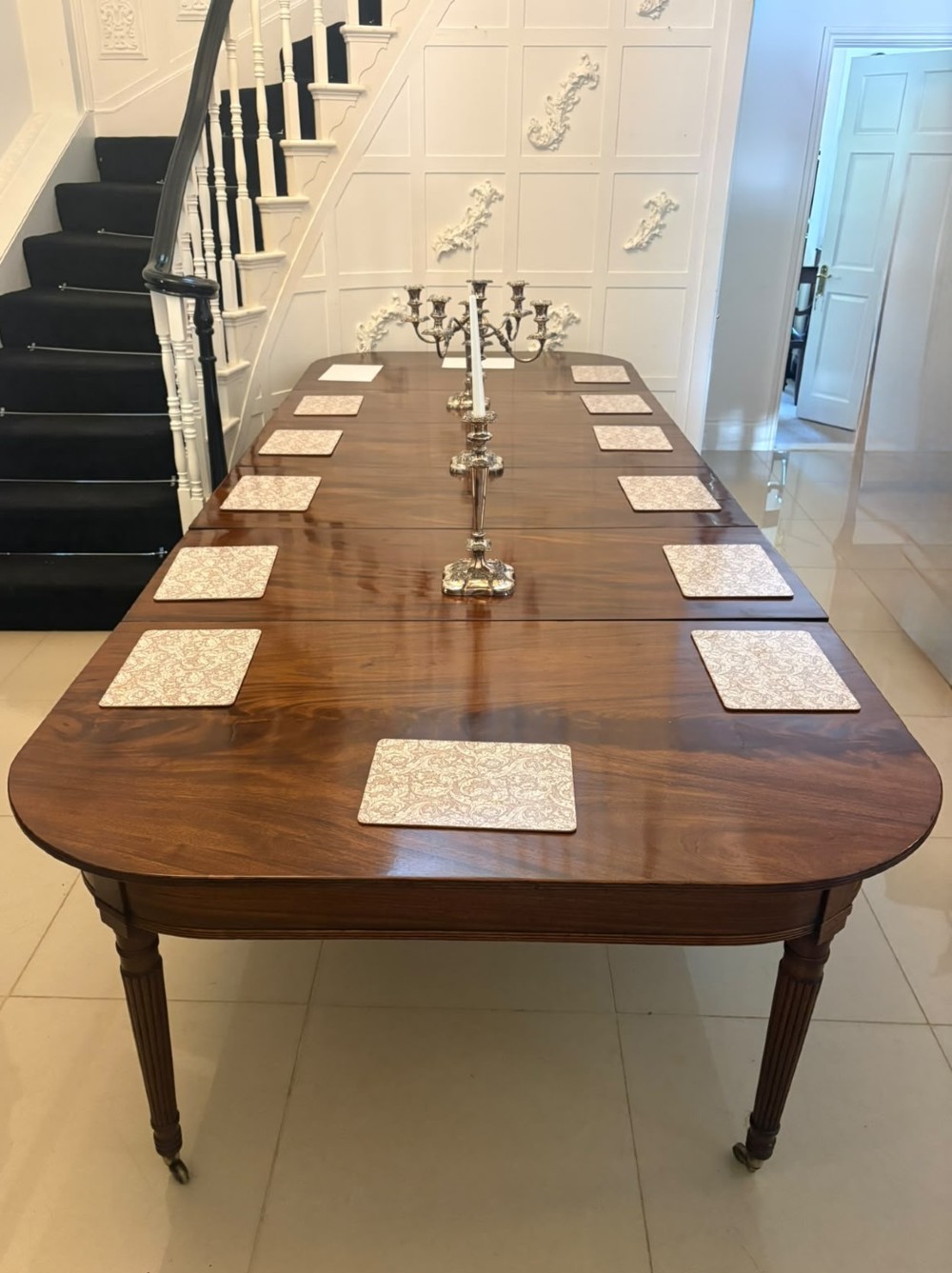 A large, polished Regency mahogany extending dining table with rounded corners and reeded legs fitted with brass castors. View VIII