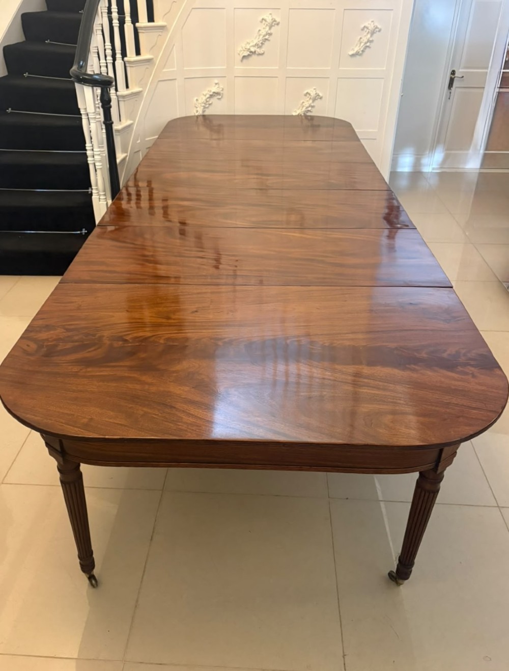 A large, polished Regency mahogany extending dining table with rounded corners and reeded legs fitted with brass castors. View IX