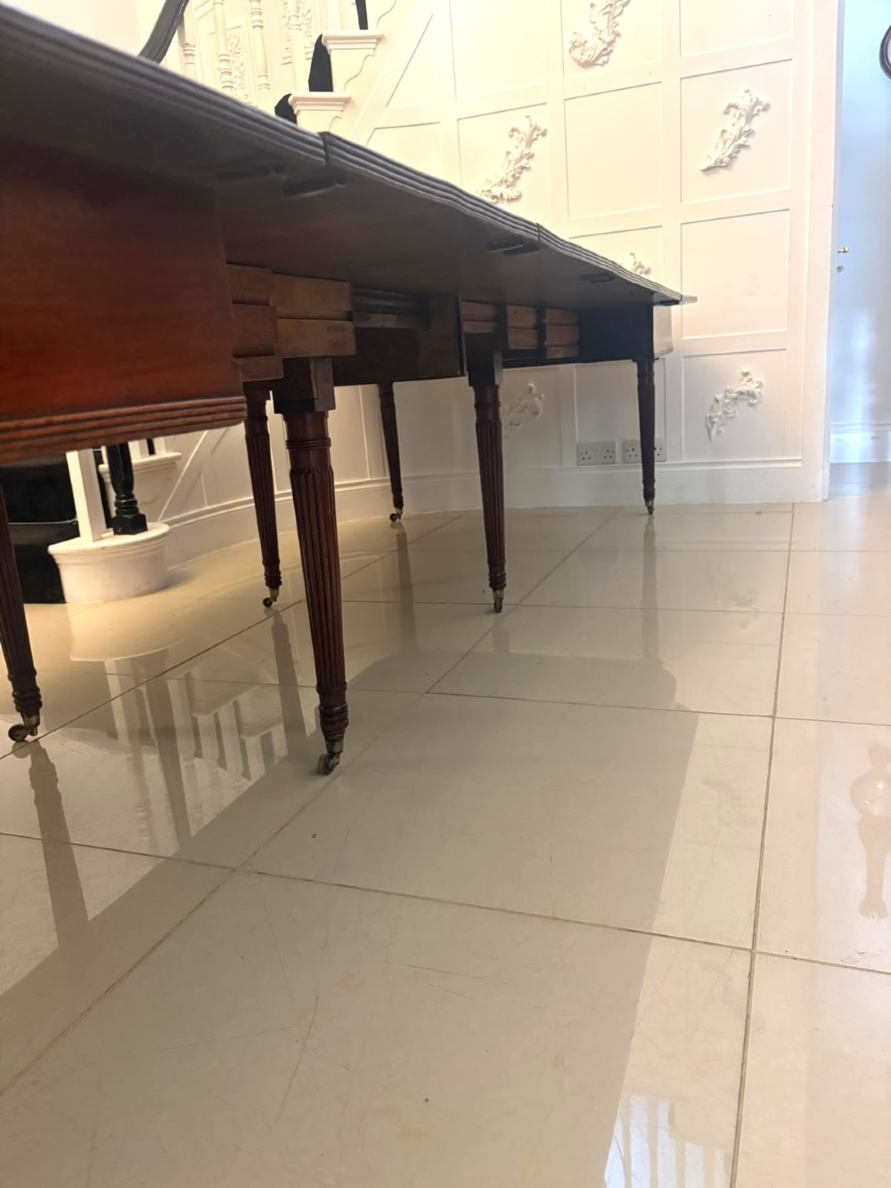 A large, polished Regency mahogany extending dining table with rounded corners and reeded legs fitted with brass castors. View XI