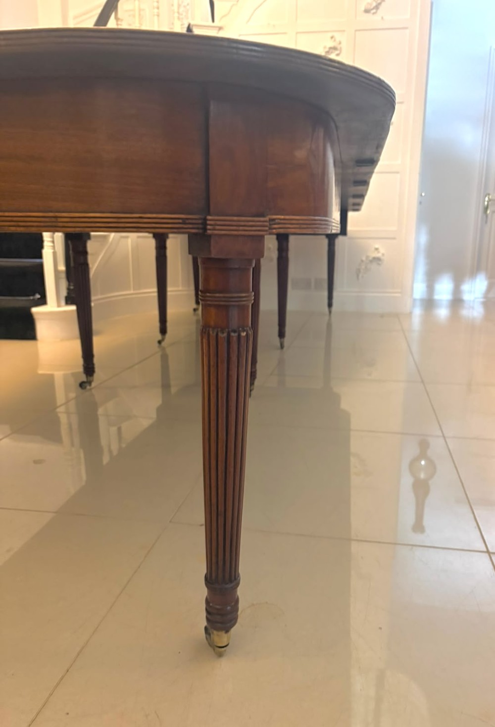 A large, polished Regency mahogany extending dining table with rounded corners and reeded legs fitted with brass castors. View XII