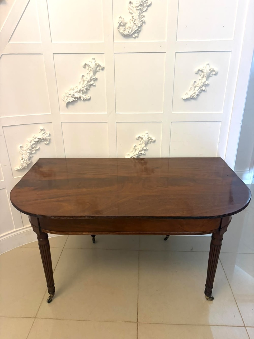A large, polished Regency mahogany extending dining table with rounded corners and reeded legs fitted with brass castors. View XIV