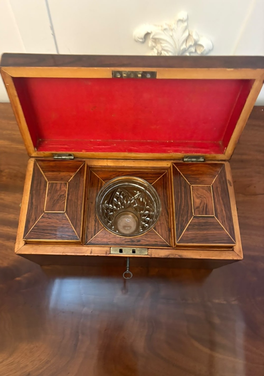 A Regency period dark rosewood tea caddy featuring brass stringing inlay, a faceted lid, and a central keyhole with key inserted. View IV