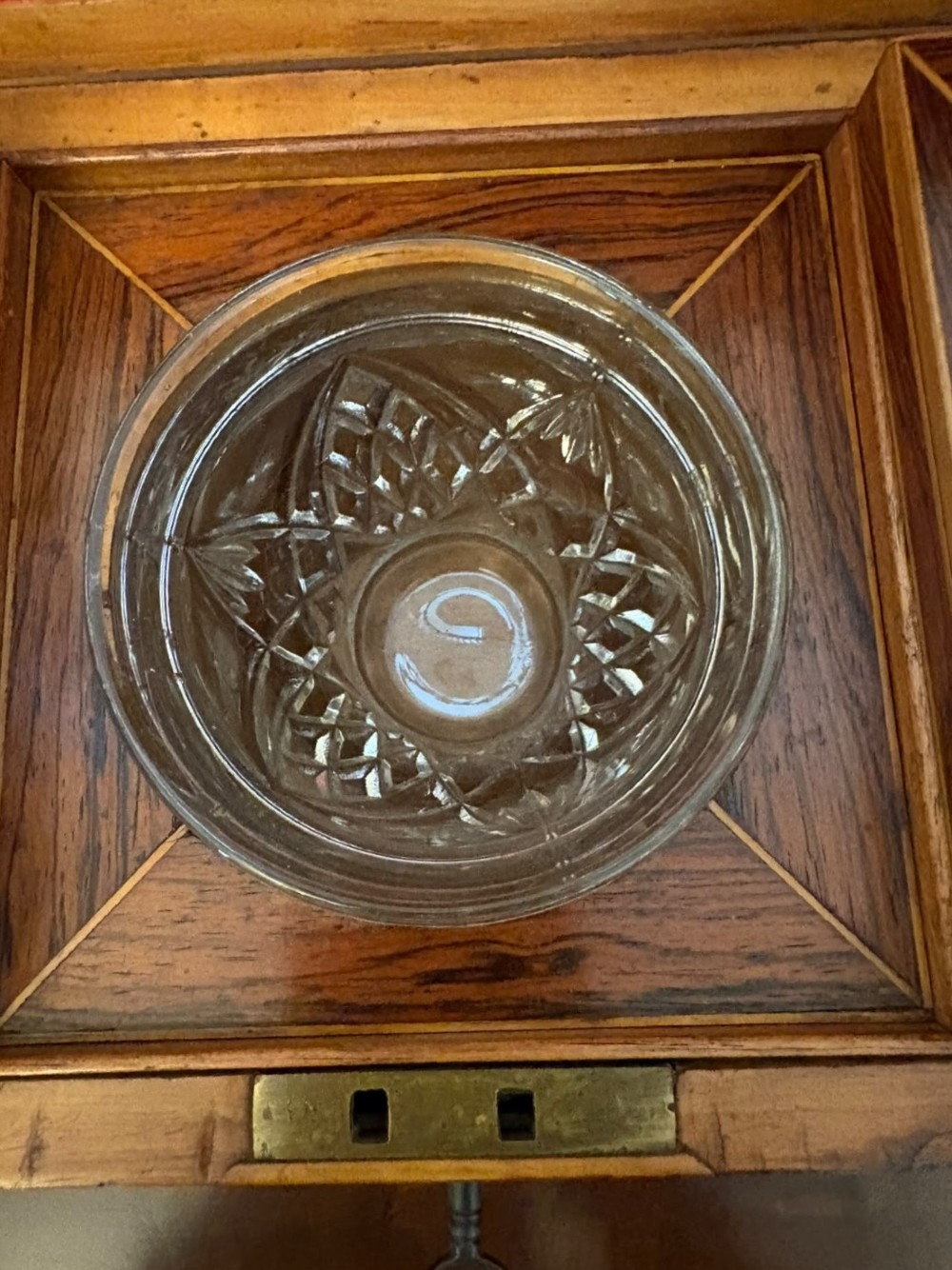 A Regency period dark rosewood tea caddy featuring brass stringing inlay, a faceted lid, and a central keyhole with key inserted. View V