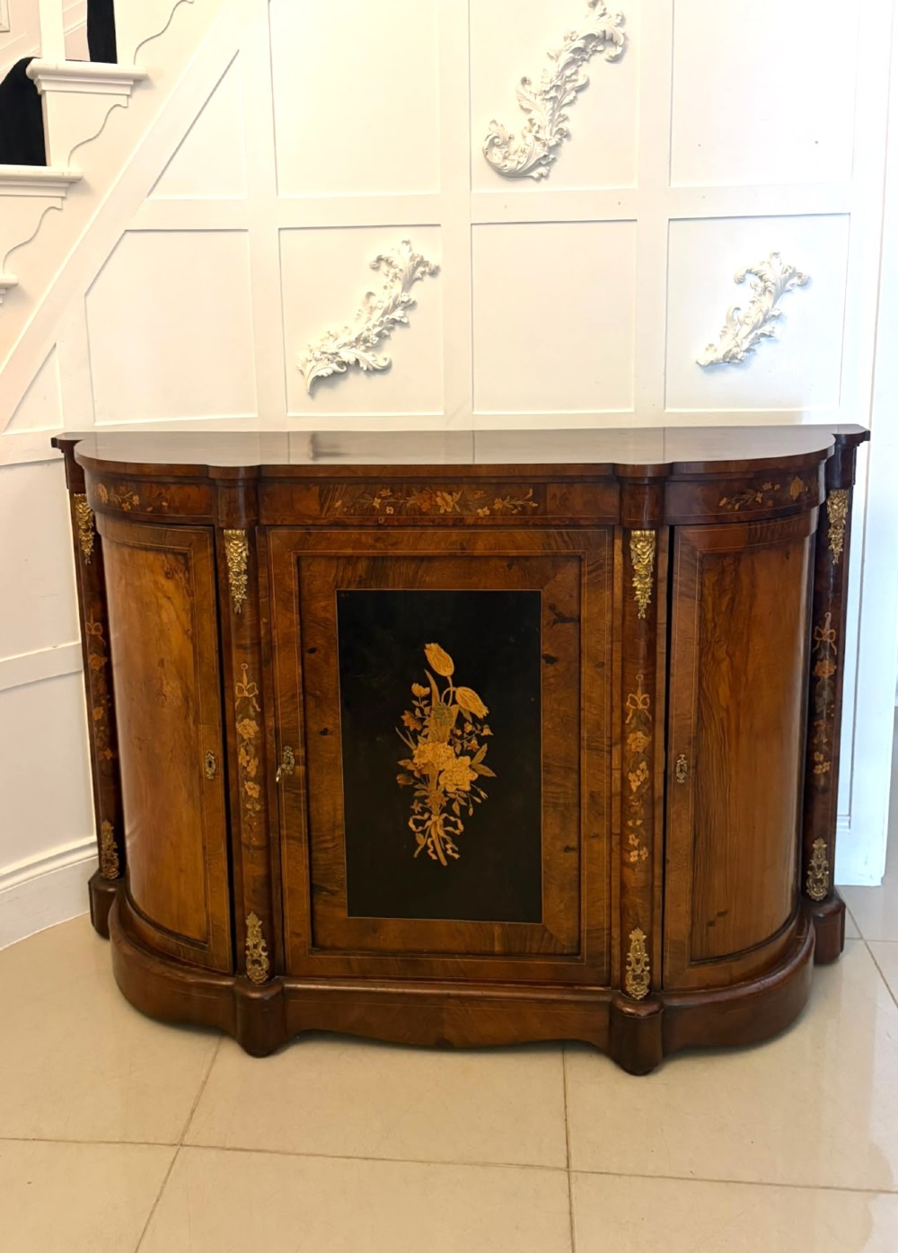 A nineteenth-century Victorian burr walnut credenza featuring curved side doors, intricate floral marquetry inlays, and gilt bronze mounts.