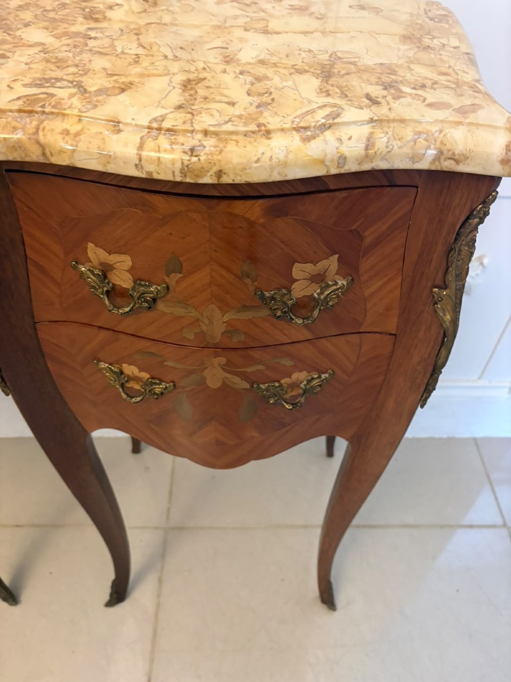 A pair of French Louis XV style kingwood bedside cabinets featuring floral marquetry inlays, gilt bronze mounts, serpentine fronts, and shaped marble tops. View XI