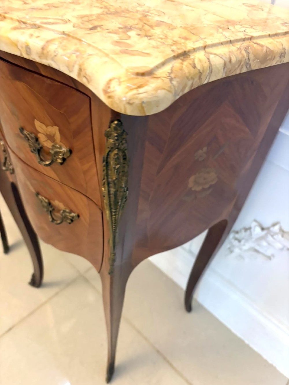 A pair of French Louis XV style kingwood bedside cabinets featuring floral marquetry inlays, gilt bronze mounts, serpentine fronts, and shaped marble tops. View XII