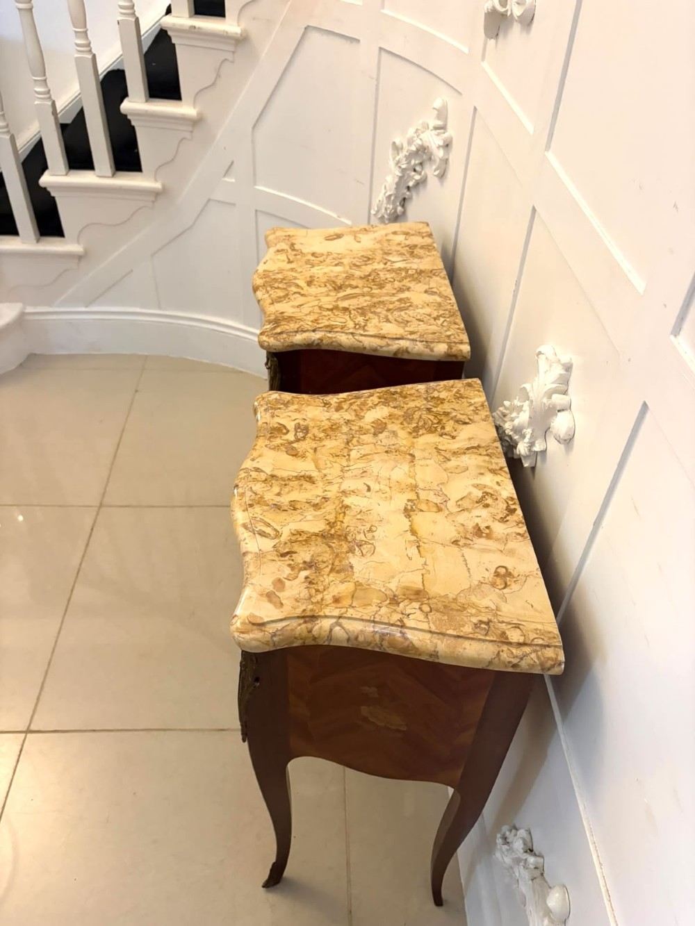 A pair of French Louis XV style kingwood bedside cabinets featuring floral marquetry inlays, gilt bronze mounts, serpentine fronts, and shaped marble tops. View XV