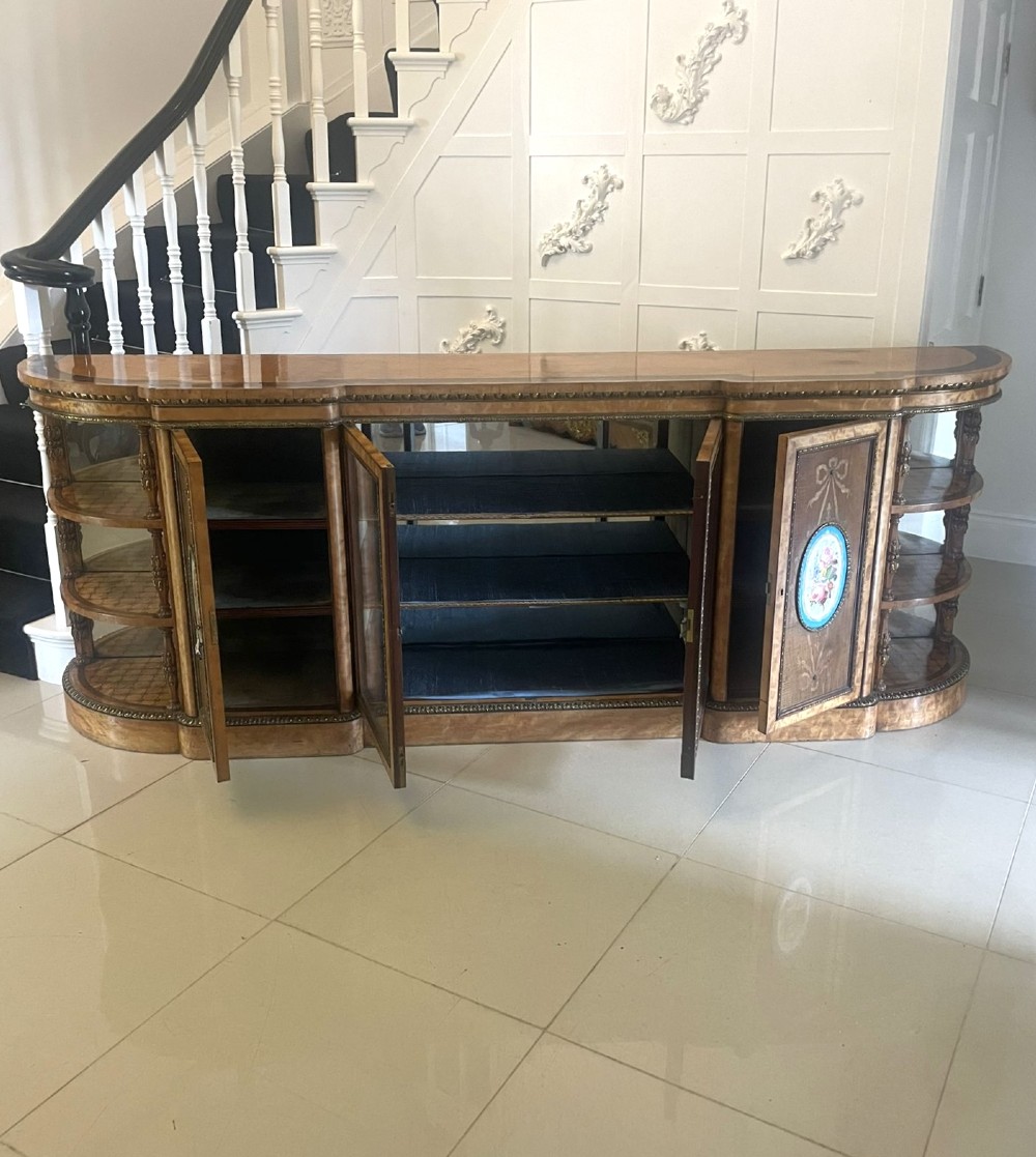 A large Victorian satinwood credenza featuring central glazed doors, oval porcelain plaques, and open curved side shelves. View XII