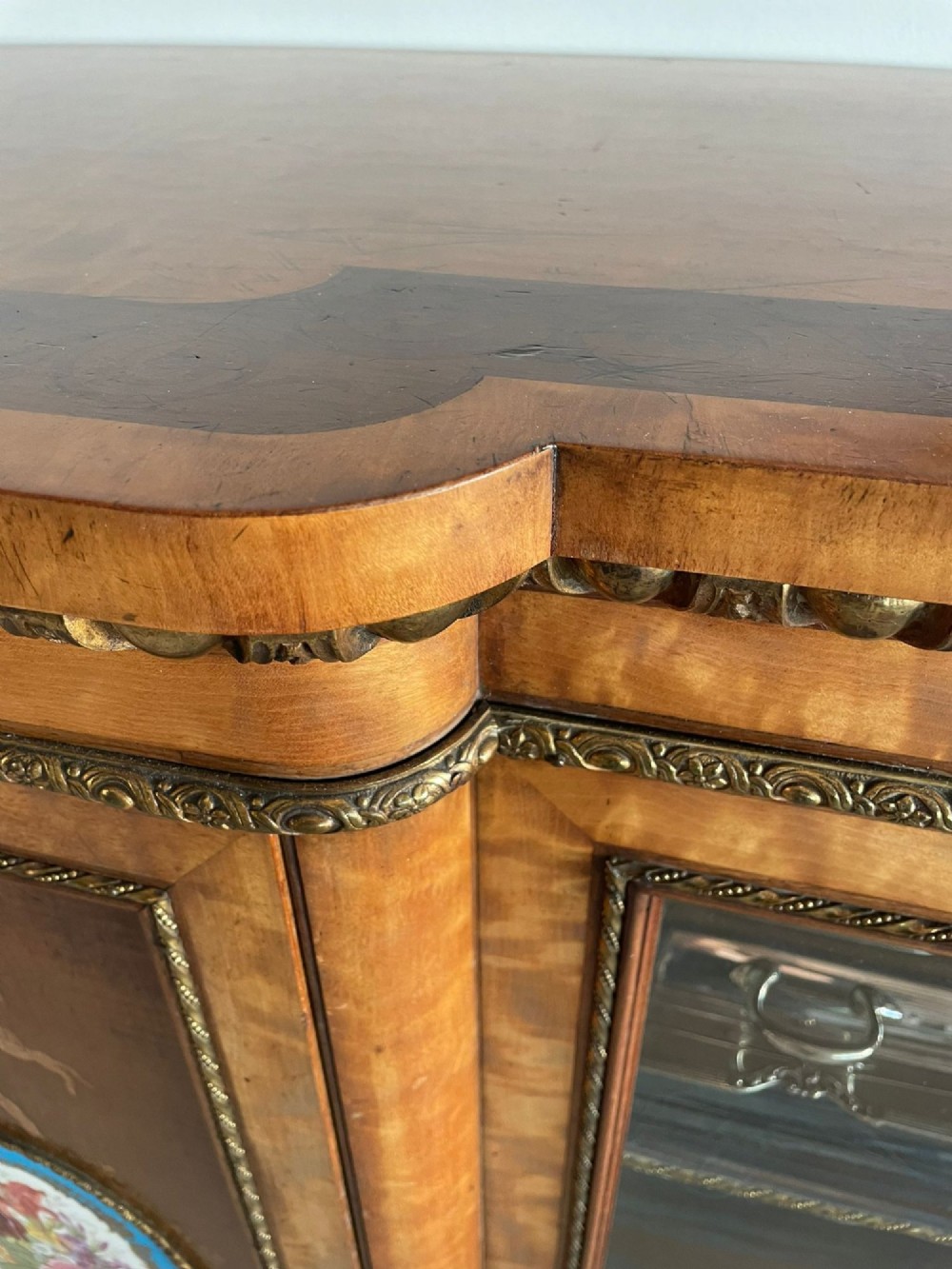 A large Victorian satinwood credenza featuring central glazed doors, oval porcelain plaques, and open curved side shelves. View XIII