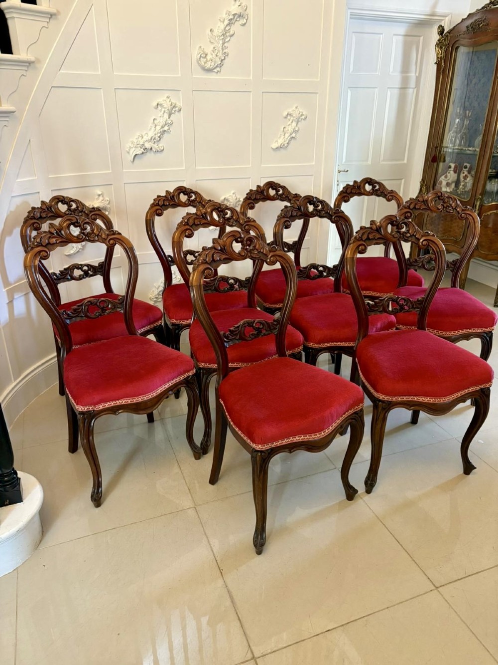 A set of Victorian carved mahogany dining chairs featuring open balloon-style backs and red velvet upholstered seats.