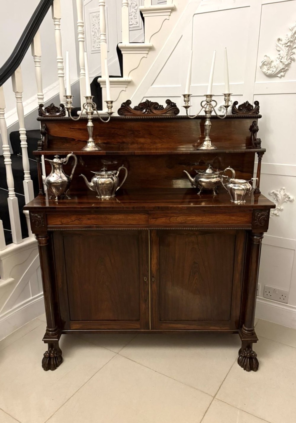 A dark mahogany Regency chiffonier sideboard featuring a two-door lower cupboard, turned support columns, carved claw feet, and a raised upper display shelf with a carved scroll cresting. View V