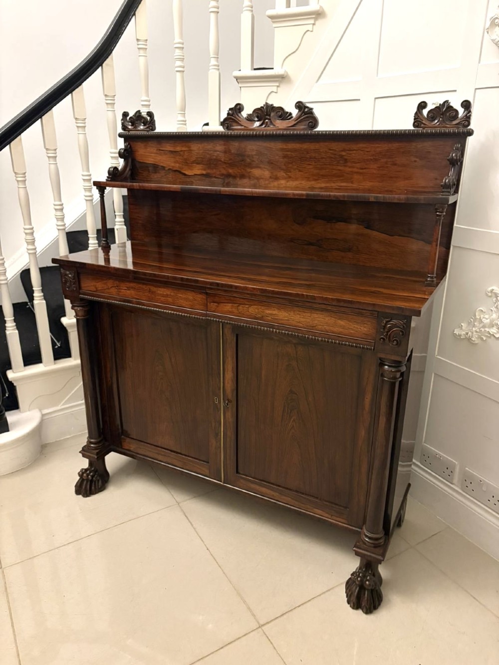 A dark mahogany Regency chiffonier sideboard featuring a two-door lower cupboard, turned support columns, carved claw feet, and a raised upper display shelf with a carved scroll cresting. View XI