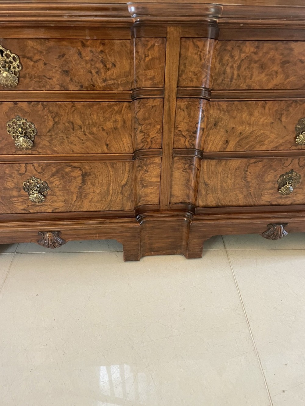A burr walnut dressing table featuring a central arched triptych mirror, highly figured wood grain, and six drawers with ornate brass handles. View XI