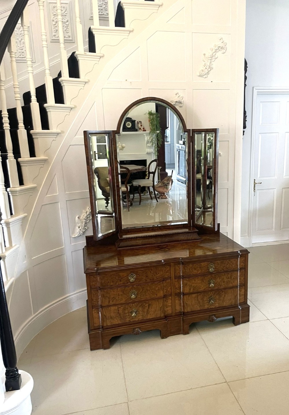 A burr walnut dressing table featuring a central arched triptych mirror, highly figured wood grain, and six drawers with ornate brass handles. View XIII