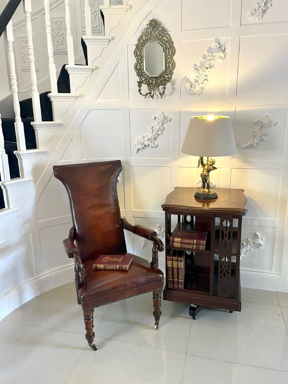 A William IV high-backed armchair upholstered in chestnut brown leather with brass stud detailing, supported by turned mahogany front legs on brass castors. View II
