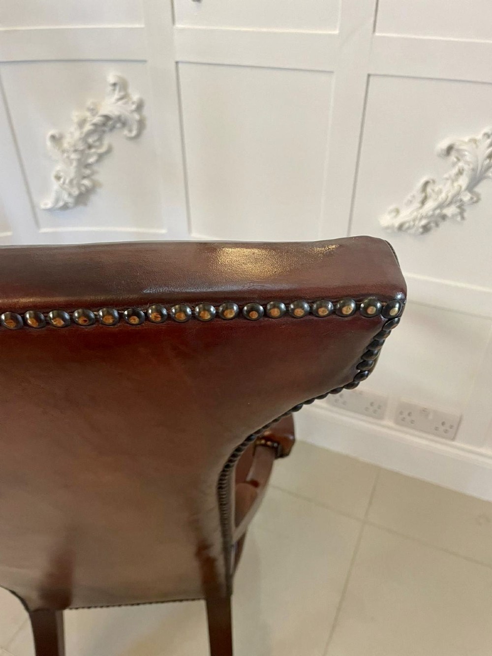 A William IV high-backed armchair upholstered in chestnut brown leather with brass stud detailing, supported by turned mahogany front legs on brass castors. View VII