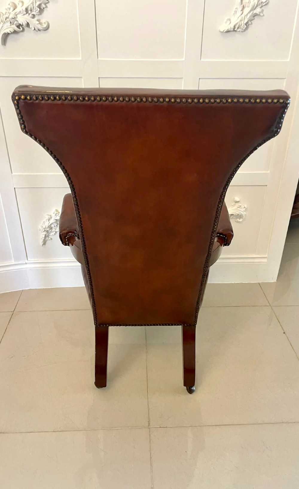 A William IV high-backed armchair upholstered in chestnut brown leather with brass stud detailing, supported by turned mahogany front legs on brass castors. View XI