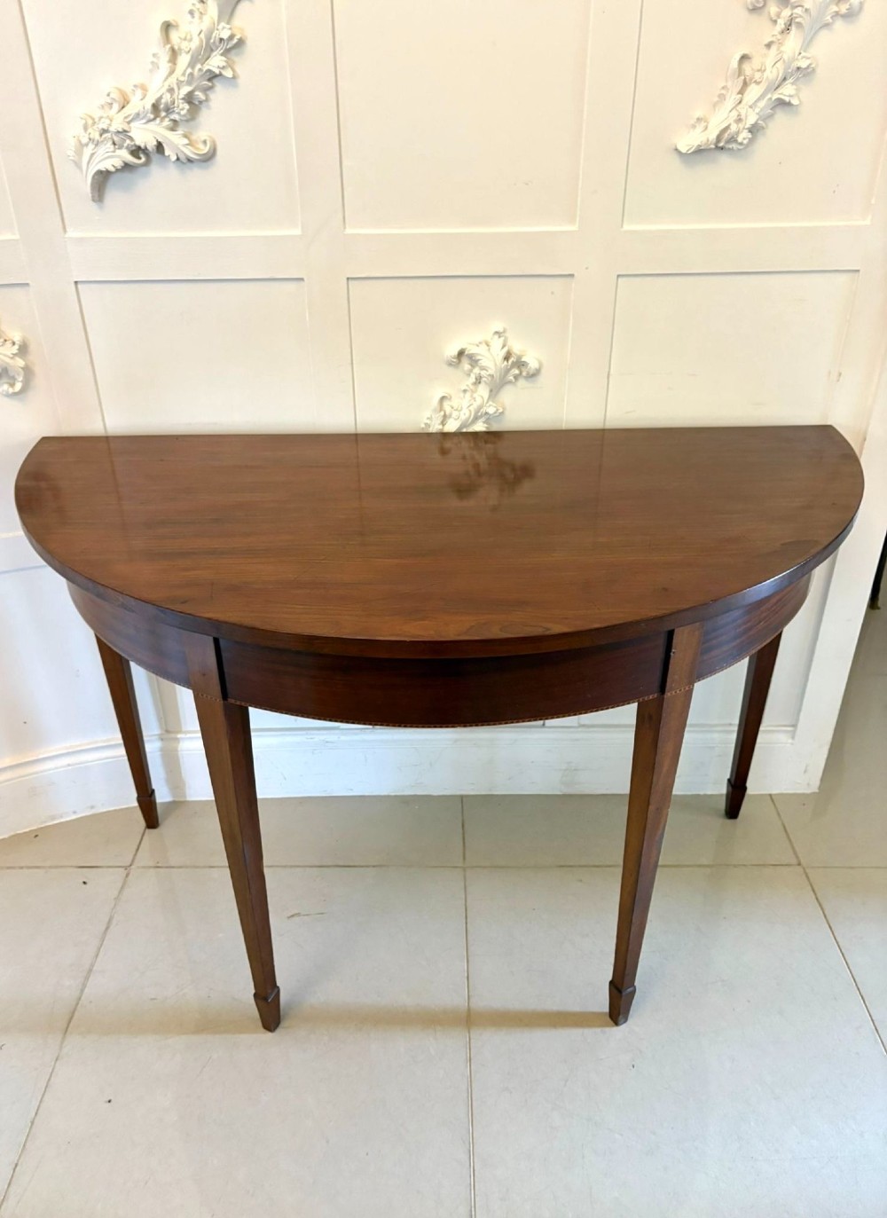 A pair of George III mahogany demi-lune console tables with polished semi-circular tops and tapered square legs. View III