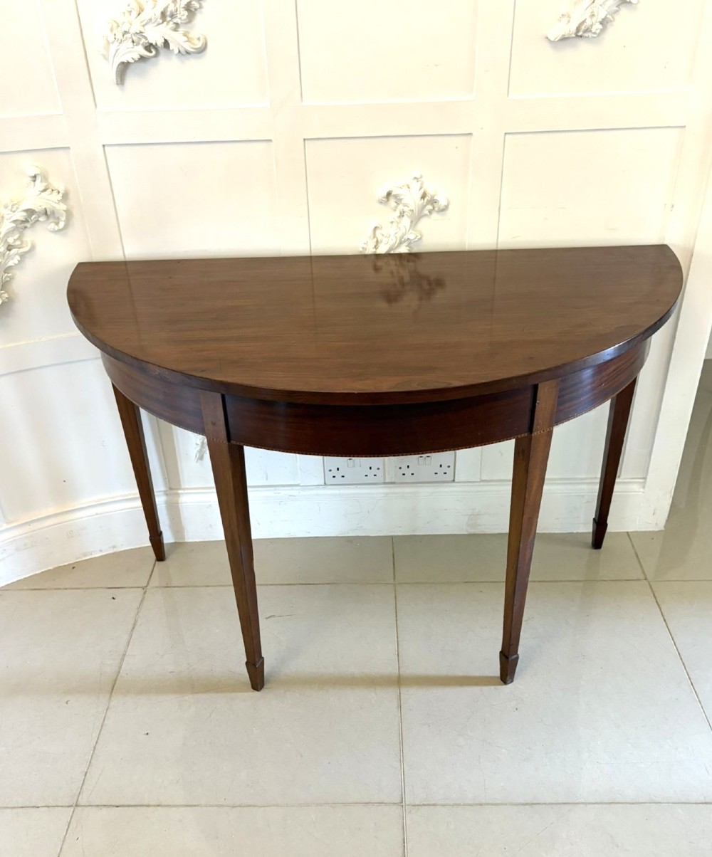 A pair of George III mahogany demi-lune console tables with polished semi-circular tops and tapered square legs. View IV