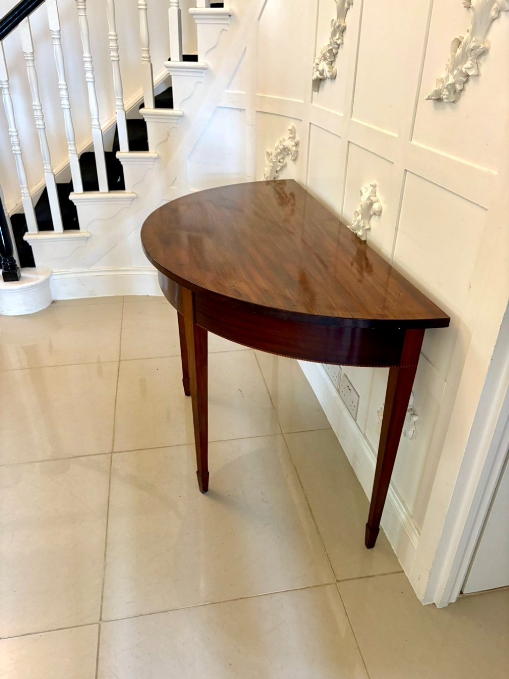 A pair of George III mahogany demi-lune console tables with polished semi-circular tops and tapered square legs. View VIII