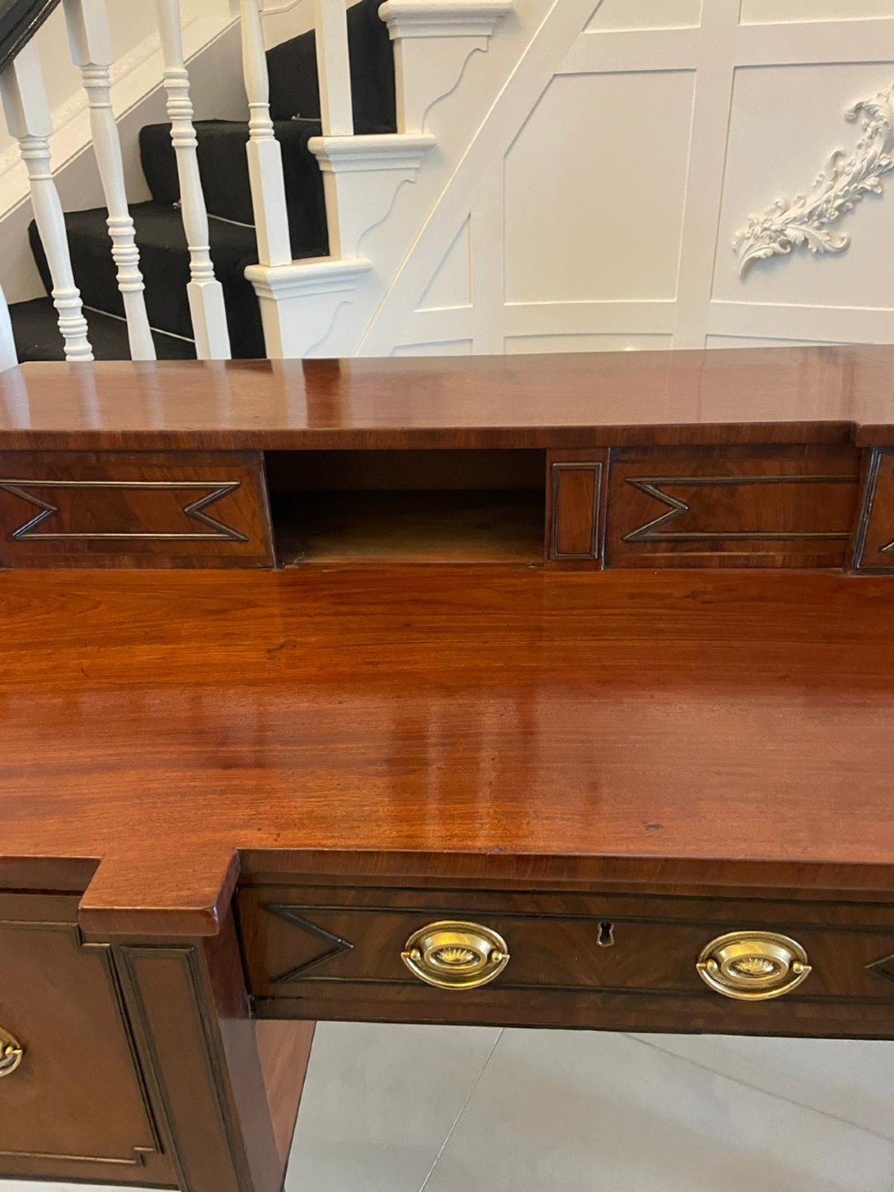 A large George III figured mahogany sideboard featuring a raised gallery, central drawers with brass handles, side cupboards, and turned reeded legs. View III