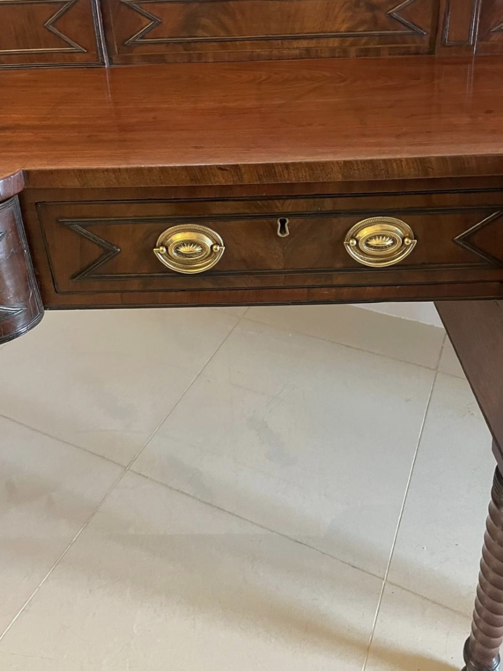 A large George III figured mahogany sideboard featuring a raised gallery, central drawers with brass handles, side cupboards, and turned reeded legs. View IX