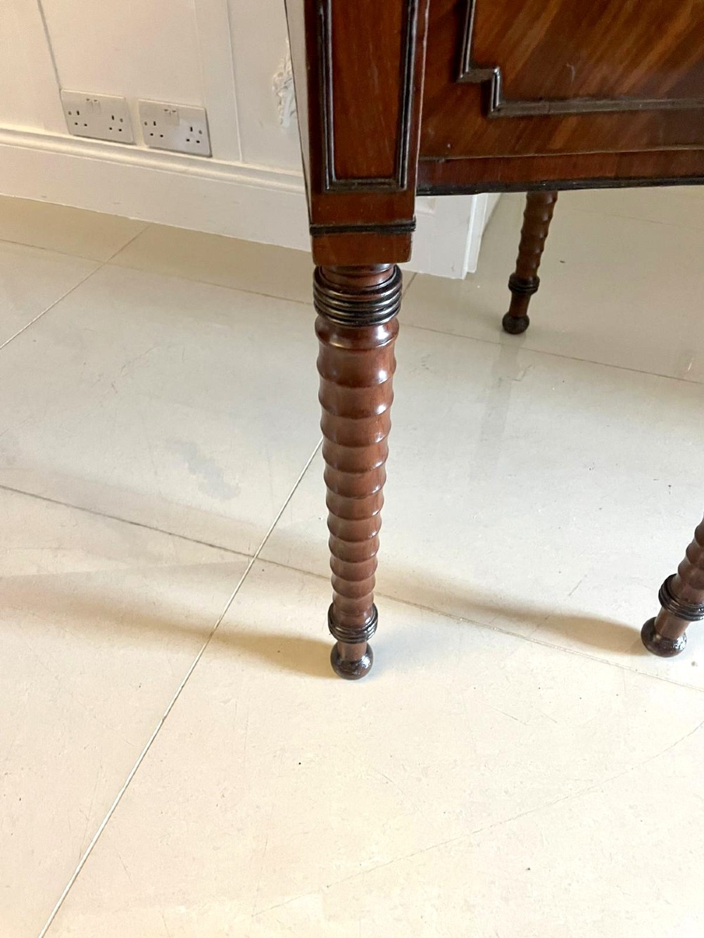 A large George III figured mahogany sideboard featuring a raised gallery, central drawers with brass handles, side cupboards, and turned reeded legs. View X