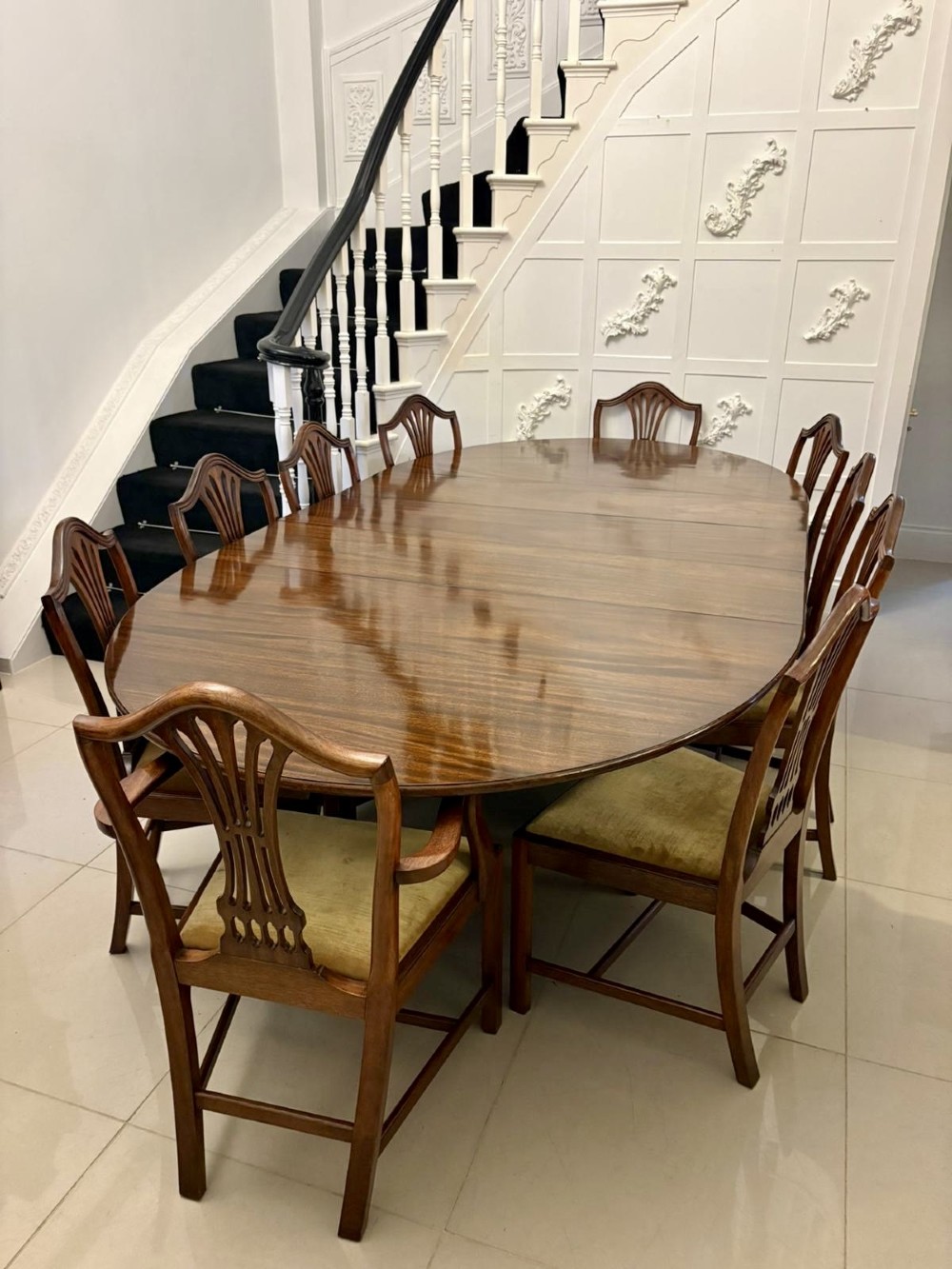 An antique oval extending mahogany dining table on splayed pedestal legs with brass castors. View II