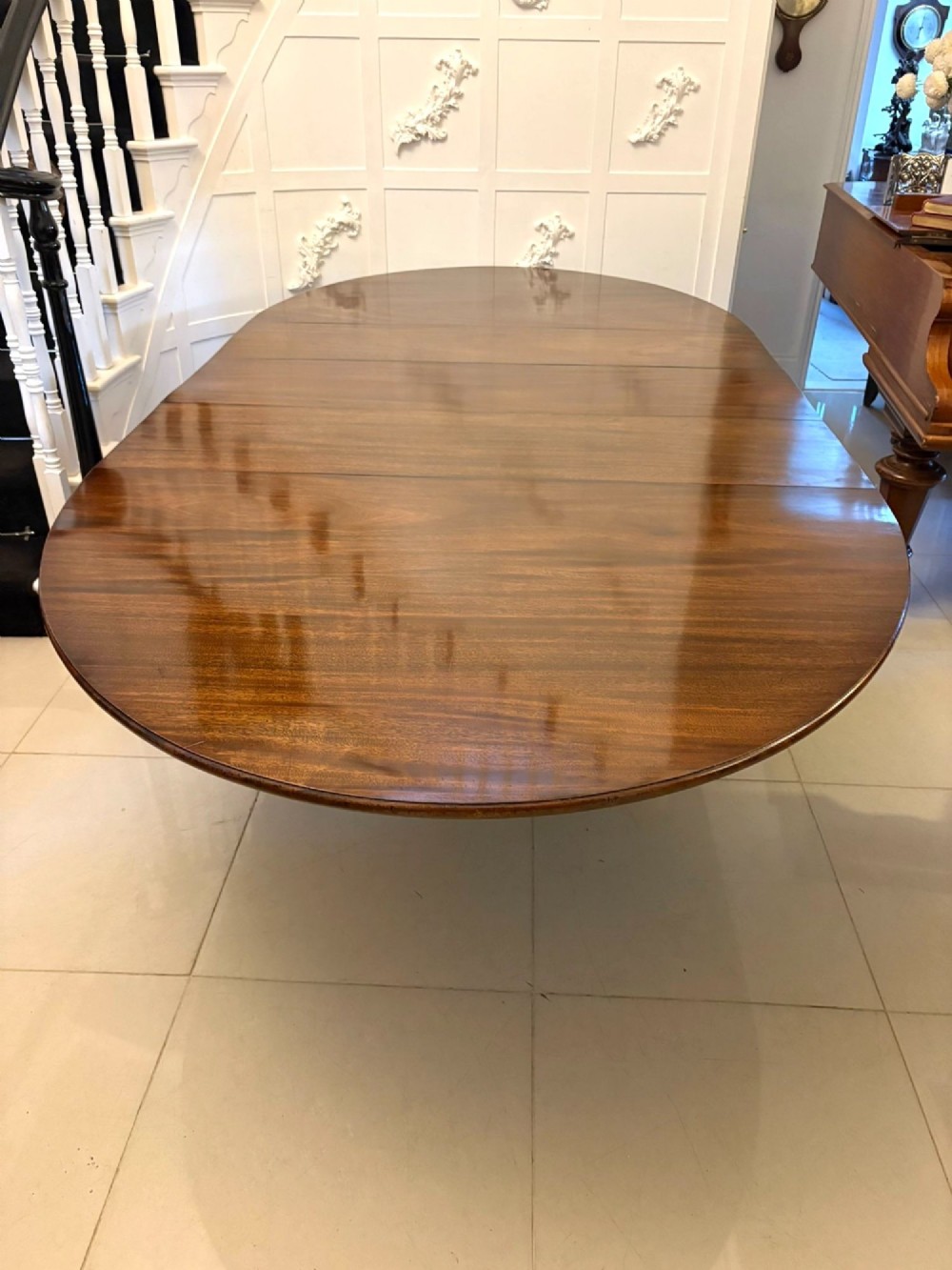 An antique oval extending mahogany dining table on splayed pedestal legs with brass castors. View V