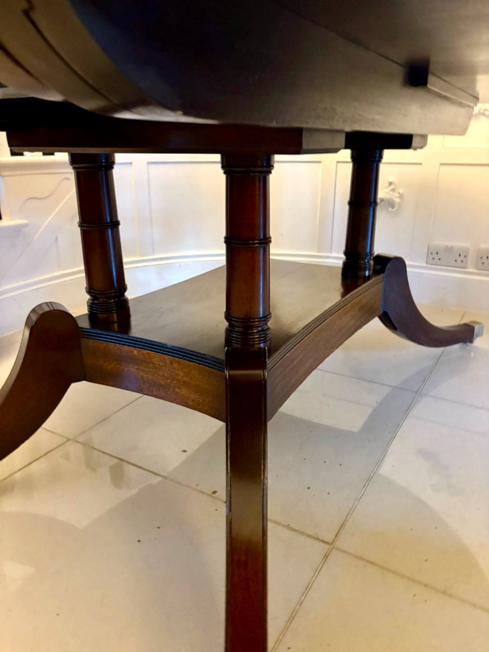 An antique oval extending mahogany dining table on splayed pedestal legs with brass castors. View X