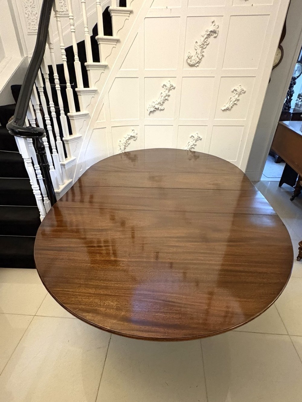 An antique oval extending mahogany dining table on splayed pedestal legs with brass castors. View XI